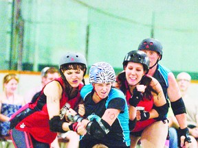 Headstone Honeys’ Bacon Blitz, left, and Tess the Mess, right, try to crush a Ring Leader Roller Girl during Saturday evening’s match at the BDO Centre for the Community.