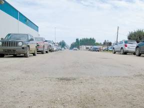 Rough and broken, the road alongside the Co-op is scheduled for paving this month but the job will not be done if construction delays costan additional $5,000 fee.