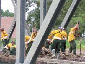 An ESRD Wildfire firefighter team clears debris from a bridge in High River after the flooding that effected large areas of southern Alberta in June.