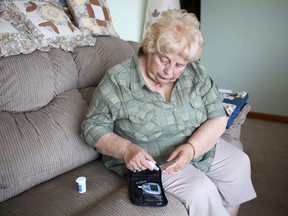 Carole Rogers checks her blood glucose level at her Kingston home Monday. The Ontario government changed the way it funds patients needing the single-use test strips, something Rogers says will make it more expensive for many people to monitor blood sugar and control their diabetes.
Elliot Ferguson The Whig-Standard