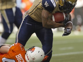 Winnipeg Blue Bombers Chad Simpson tries to break the tackle of BC Lions Adam Bighill earlier this season. (Richard Lam/QMI Agency file photo)