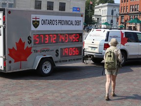 A woman walks past the Canadian Taxpayers Federation debt clock, which stopped in Kingston Wednesday morning. The clock displays what the federation says is Ontairo's growing public debt in real time.
Elliot Ferguson The Whig-Standard