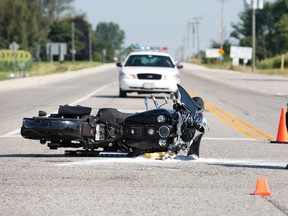 A member of the London Police Department photographs wreckage after a motorcycle collided with a car at the intersection of Colonel Talbot Road and Littlewood Drive in London, Ontario on Monday, August 19, 2013. (DEREK RUTTAN QMI Agency)