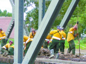 An ESRD Wildfire firefighter team clears debris from a bridge in High River after the flooding that effected large areas of southern Alberta in June.
Submitted