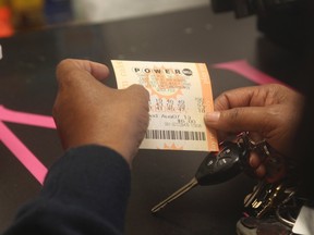A woman holds her  Powerball lottery ticket at  the Bluebird Liquor store in Hawtorne, California August 7, 2013. (REUTERS/Fred Prouser)