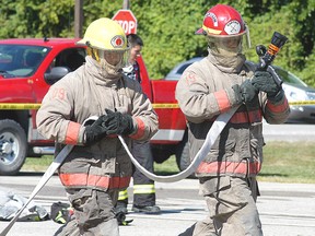 Walpole Island's Cyril Peters, left, and Bobby Smith take part in the Aboriginal Firefighters Association of Canada national fire competition at the Walpole Island Sports Complex on Saturday. The competition involved firefighters taking part in a number of firefighting duties. Walpole Island finished fifth out of eight teams in the one-day competition. (DAVID GOUGH, QMI Agency)