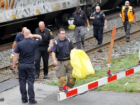 A Belleville, Ont. firefighter carries a yellow bag containing unknown items, which was placed into a fire truck, after a 21-year-old Belleville man, police said, sustained life threatening injuries after he was struck by a train near the Geddes Street crossing (above) in Belleville, Ont. Tuesday morning, Aug. 27, 2013.  JEROME LESSARD/The Intelligencer/QMI Agency