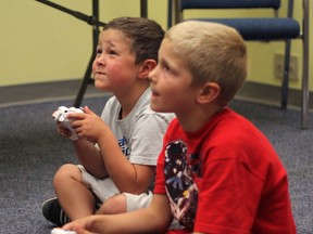 KASSIDY CHRISTENSEN VULCAN ADVOCATE/QMI AGENCY Brothers Solomon (back) and Titus Stelter test out the newly acquired Xbox gaming system at the Vulcan Municipal Library Tuesday.