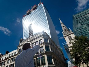 A man reacts to a shaft of intense sunlight reflected from the glass windows of the new "Walkie Talkie" tower in central London on August 30, 2013. (AFP PHOTO/LEON NEAL)