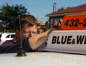 Colin Williams a technician for Aboutown screws down a new Blue & White light on a cab in the Aboutown office on Carling St. MIKE HENSEN/The London Free Press/QMI AGENCY