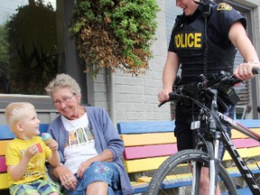 Const. Ginger Buttery with the Lambton OPP in Point Edward, stops to chat with Sally Duncan, 75, and her great-grandson Jaxen Skinner, 3, as the youngster enjoys some ice cream. The village detachment is stepping up its bicycle patrol training for officers, after recently acquiring a pair of new bikes. (TYLER KULA, The Observer)