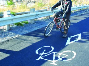 Kenora Urban Trails Bicycle Routes committee chairman Dave Schwartz astride his favourite mode of transportation by one of the stencils designating the dedicated bicycle lanes in Kenora.