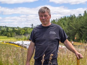 Dan Walker stands on his land near Grafton, Ont. Behind him tarps cover soil he says was contaminated by oil. 
Sam Koebrich for The Whig-Standard