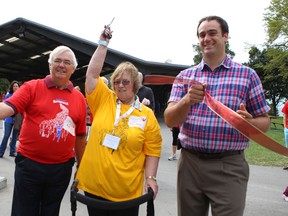 Palmier Stevenson-Young, president of the Kingston Branch of the Parkinson Society Canada, cuts the ribbon to open Saturday’s Parkinson Society SuperWalk, with some help from Kingston and the Islands MPP John Gerretsen, left, and Kingston Mayor Mark Gerretsen. (Elliot Ferguson/The Whig-Standard)