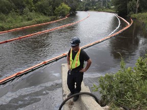 A cleanup worker watches the absorbent booms collecting oil from the Kalamazoo River after an oil pipeline, owned by Enbridge Energy Partners, leaked an estimated 820,000 gallons of oil into the Kalamazoo River in western Michigan, near Marshall, in July 2010. (Rebecca Cook/Reuters)