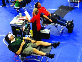 Two men give blood at the mobile clinic set up at St. Thomas Aquinas Secondary School on Monday, Sept. 9. Monday’s target was 138 donors and the clinic was continuing until noon Tuesday.