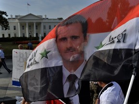 Supporters of Syrian President Bashar Al-Assad wave a Syrian flag with featuring the leader's face during a demonstration in front of the White House in Washington on September 9. AFP Photo/Jewel Samad