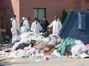 London police search a dumpster behind the Travelodge London South on Exeter Rd. Tuesday as they continue their investigation of the slaying of a man whose body was discovered in a room at the hotel Sunday. (DEREK RUTTAN, The London Free Press)