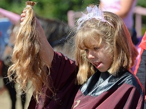 Emma VanParys, 10, holds up her just-cut hair to be donated for cancer-patient wigs.