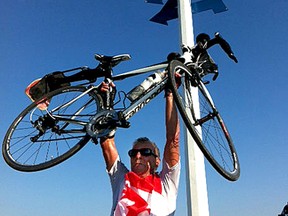 Jim Brooks lifts his bike after arriving at Signal Hill, near St. John's, Nfld., after completing a cross-Canada cycle ride.
