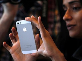 A woman tries the silver coloured version of the new iPhone 5S after Apple Inc's media event in Cupertino, Calif. Sept. 10, 2013. REUTERS/Stephen Lam