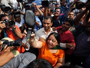 A protester threatens to throw her sandal at A.P. Singh (not in picture), defence lawyer of one of the four men convicted of raping and murdering a 23-year-old trainee physiotherapist last December, during a protest outside a court in New Delhi September 11, 2013. (REUTERS/Adnan Abidi)
