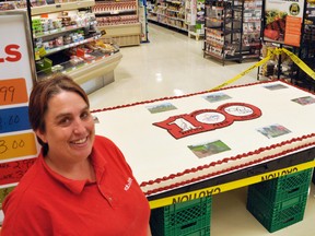 Shannon Pilkington, bakery manager at Valu-mart in Mitchell, stands next to a giant 100th International Plowing Match (IPM) & Rural Expos cake, made by Laura Nutt and Mary Vorstenbosch of Tavistock.