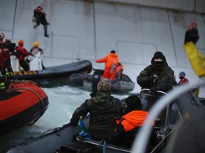 According to Greenpeace, a masked man identified as a Russian coast guard officer (R) points a gun at a Greenpeace International activist, during a protest near a Gazprom oil platform in the Pechora Sea September 18, 2013.  REUTERS/Denis Sinyakov/Greenpeace/Handout via Reuters