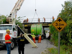 A crew of CN Rail workers cut a recycling truck free from under the Subway Line rail overpass after it hit the bridge and got stuck. Subway Line will be closed between Highway 2 and Highway 53 until repairs to the bridge are completed sometime Friday evening.