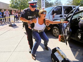 Belleville Police Sgt. Rene Aubertin restrains Gina McNevin, playing the role of a woman who's just lost her daughter to a collision with a drunk driver, as she runs through a mock crash scenario at Loyalist College in Belleville Thursday. The scenario was organized by a multi-agency group that aims to teach students the consequences of irresponsible drinking.