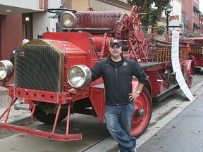 FireFest co-chair Brent DeNure poses with a 1925 American LaFrance tiller aerial firetruck once owned by the West New York, New Jersey Fire Department. The truck features solid rubber tires and front wheel chain drive.