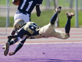 Catholic Central?s Kwaku Antwi runs in  touchdown pass from Cameron Geddes as Regina Mundi?s Jason Creces tries a diving tackle during CCH?s 68-7 win over Regina Mundi Thursday in a United Way game at TD Stadium. (MIKE HENSEN The London Free Press)