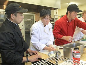 Chef Guy Seh, left, offers some tips to LCVI cook's internship focus program students Sarah Giddy, Luke Lanoue and Justin Whidden in the high school kitchen Thursday afternoon. Seh is the chef at the K-Rock Centre and is part of a mentorship program.
Michael Lea The Whig-Standard