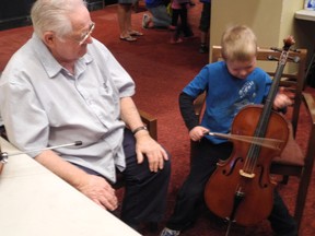 Volunteer Jim Coles keeps a watchful eye on Ryan MacIntosh, 5, as he tries his hand at playing the cello during the Kingston Symphony Association-organized Instrument Petting Zoo held Saturday in the lobby of the Grand Theatre as part of the city’s Culture Days celebration. (PETER HENDRA The Whig-Standard)