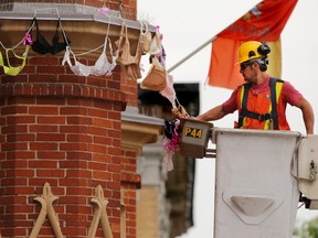 City worker Mike Butler hangs bras around the second-floor ledge of Belleville city hall Monday. The Canadian Cancer Society collected more than 1,000 donated bras for Bras in the Breeze, a Tuesday event promoting the need for regular mammogram screening for breast cancer.