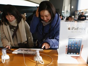 Visitors try Apple Inc's iPad mini at an electronics store in central Seoul Jan. 18, 2013. REUTERS/Lee Jae-Won