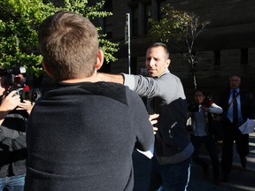 Sandro Lisi swings at a National Post photographer after being released from jail on Oct. 2, 2013. (Stan Behal/Toronto Sun)