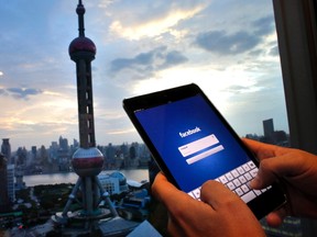 In this photo illustration, a man holds an iPad with a Facebook application in an office building at the Pudong financial district in Shanghai, September 25, 2013 file photo. REUTERS/Carlos Barria