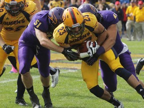 Queen’s Golden Gaels’ Doug Corby gets tackled by Laurier’s Zachary Hoare, left, and Darian Waite during Saturday’s 40-34 overtime win by the Gaels. (Elliot Ferguson The Whig-Standard)