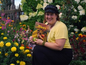 Kari-Lynn Winters, a St. Thomas native and Brock University professor, holds a copy of her book Buzz About Bees in a garden at Clovermead Adventure Farm near Aylmer. Winters wrote the book to educate children about declining bee populations.