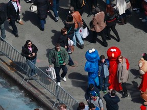 People pose for photos with characters dressed up as Elmo and Cookie Monster in Times Square in New York, March 30, 2013.  REUTERS/Carlo Allegri