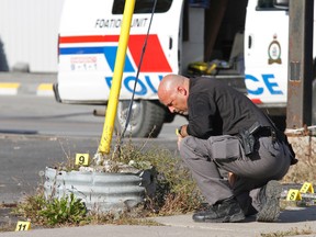 A forensic technician with Belleville police gathers evidence at the scene of a hit and run at the intersection of Coleman Street and Moira Street Thursday afternoon, Oct. 10, 2013, where a 46-year-old Belleville, Ont. woman was seriously injured in the night of Wednesday, Oct. 9 to Thursday, Oct. 10, 2013. - JEROME LESSARD/The Intelligencer/QMI Agency