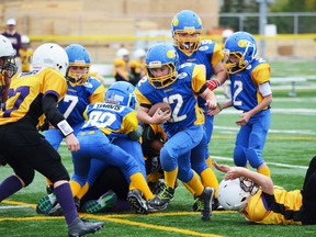 Caiden Tremblay of the Stony Plain atom Bombers (in blue) gains some ground up the middle against St. Albert. - Thomas Miller, Reporter/Examiner