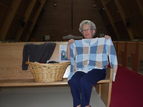Donna Anderson of Redeemer Lutheran Church in St. Thomas holds a sweater in the church sanctuary on Saturday. The church is collecting sweaters to help Syrian refugees make it through the winter. Ben Forrest/QMI Agency/Times-Journal