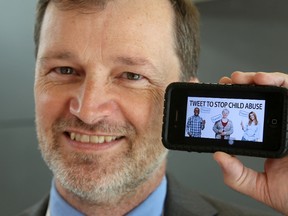 Steve Woodman, the executive director of Family and Children's Services of Frontenac, Lennox and Addington, holds a smart phone that he will use to tweet against child abuse on Oct. 18. (Ian MacAlpine The Whig-Standard)