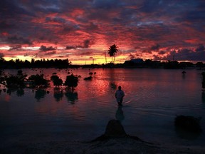 A villager wades through a small lagoon, which at high-tide laps at the base of homes, near the village of Tangintebu on South Tarawa in the central Pacific island nation of Kiribati May 25, 2013. (REUTERS/David Gray)