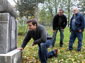 Queen's student Ian Longo with professor George Bevan (rear, left) and professor Emeritus Rowland Tinline, look over a weathered gravestone at the Cataraqui Cemetery in Kingston on Thursday. They have come up with a way of photo enhancing old gravestones so they're readable. 
IAN MACALPINE/KINGSTON WHIG-STANDARD/QMI AGENCY