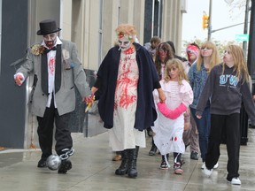 Stacey Bassett, left, and Judy Beresford, right, lead a procession of zombies through downtown Sarnia Saturday. Afternoon showers couldn't stop horror fans from participating in the Sarnia library's annual Zombie Walk.