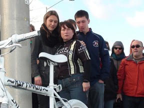 A memory bike at the southwest corner of Merivale and Hunt Club roads Sunday, Oct. 20, 2013 honours cyclist Mario Theoret, as best friend Cat Weaver (right) is comforted by her children. The 38-year-old cyclist was killed after colliding with a tractor trailer last Thursday as he rode to work at a high-tech firm. KELLY ROCHE/OTTAWA SUN