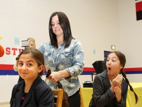 Alyssa Derro, right, 10, reacts as her sister, Ava, 8, has her hair cut by Christina Bruno at a St. James School assembly in Lively, ON., on Monday, October 21, 2013. Both girls had their hair cut so they could donate their hair to the Angel Hair for Kids program, where the hair will be used to make wigs for children being treated for cancer. The girls, who are related to the late Sam Bruno, collected money for the Sam Bruno P.E.T. Scan Fund. See video at www.thesudburystar.com JOHN LAPPA/THE SUDBURY STAR/QMI AGENCY